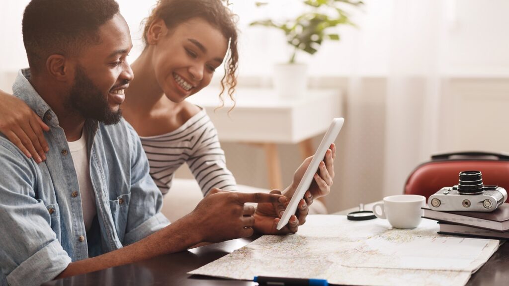 couple regarde son écran et une carte et fait sa visite immobilière à distance