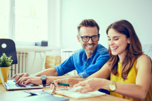 Couple devant son ordinateur en train de faire des calculs et des papiers